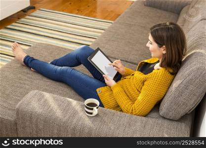 Beautiful woman working at home with a tablet and drinking coffee