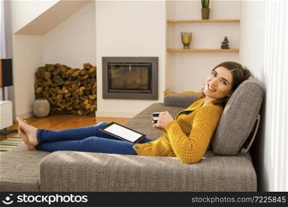 Beautiful woman working at home with a tablet and drinking coffee
