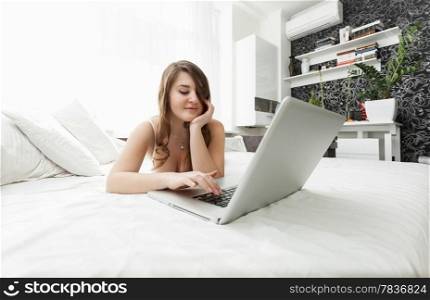 Beautiful woman working at home with laptop in bed