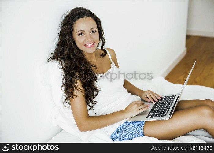 Beautiful woman working with a laptop on the bed