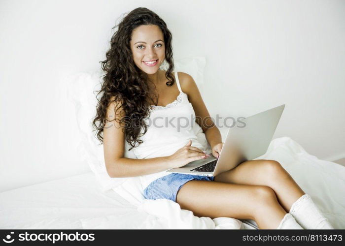 Beautiful woman working with a laptop on the bed