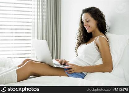 Beautiful woman working with a laptop on the bed