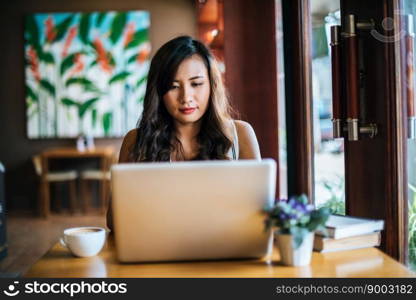 Beautiful woman working with laptop computer at coffee shop cafe