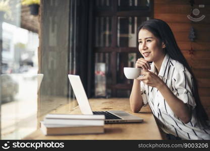 Beautiful woman working with laptop computer at coffee shop cafe