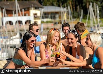 Beautiful women in bikinis toasting with cocktails at beach