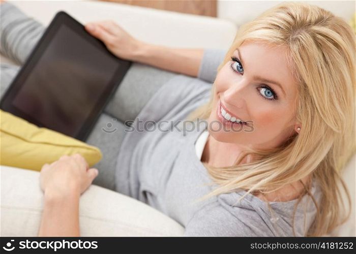 Beautiful Women Using Tablet Computer At Home on Sofa
