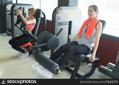 beautiful women working out legs on machine in a gym