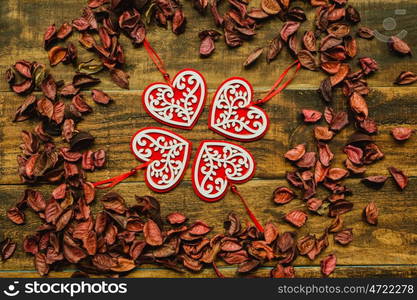 Beautiful wooden hearts with red dry petals around on a rustic wood