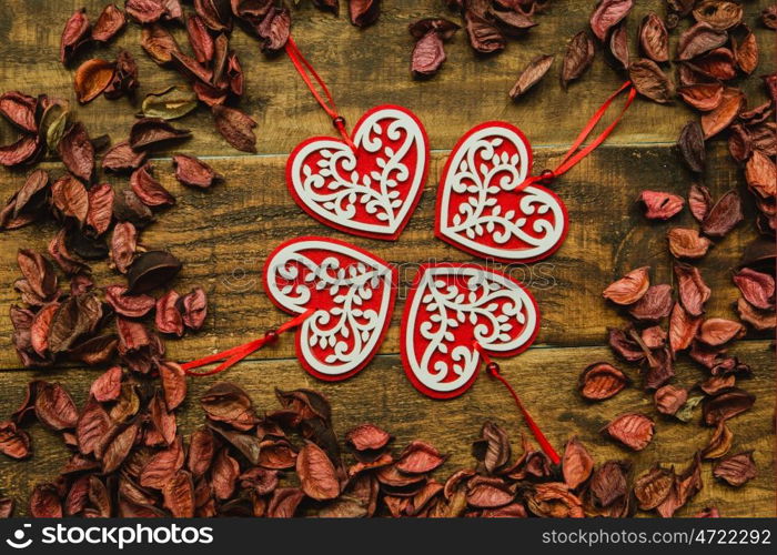 Beautiful wooden hearts with red dry petals around on a rustic wood