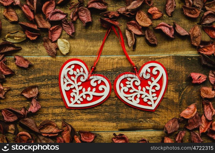 Beautiful wooden hearts with red dry petals around on a rustic wood