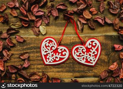 Beautiful wooden hearts with red dry petals around on a rustic wood