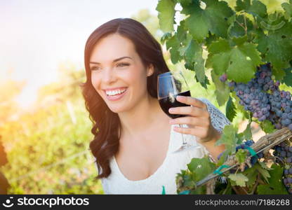 Beautiful Young Adult Woman Enjoying Glass of Wine Tasting In The Vineyard.