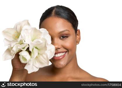 Beautiful young African American female model with stylish natural makeup covering half of face with delicate white flowers and looking at camera with toothy smile. Happy woman with makeup and flowers