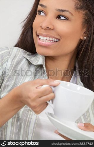 Beautiful young African American woman or girl smiling, relaxing and drinking a cup of coffee or tea