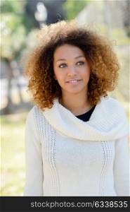 Beautiful young African American woman with afro hairstyle and green eyes wearing white winter dress