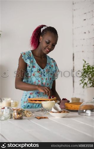 Beautiful young african woman cooking cake at kitchen
