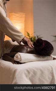 Beautiful young african woman enjoys body back massage in a luxury spa resort
