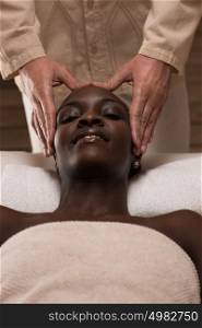 Beautiful young african woman enjoys facial massage in a luxury spa resort