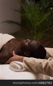 Beautiful young african woman enjoys shoulders massage in a luxury spa resort