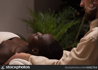 Beautiful young african woman enjoys shoulders massage in a luxury spa resort