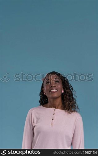 Beautiful young african woman looking up on blue background