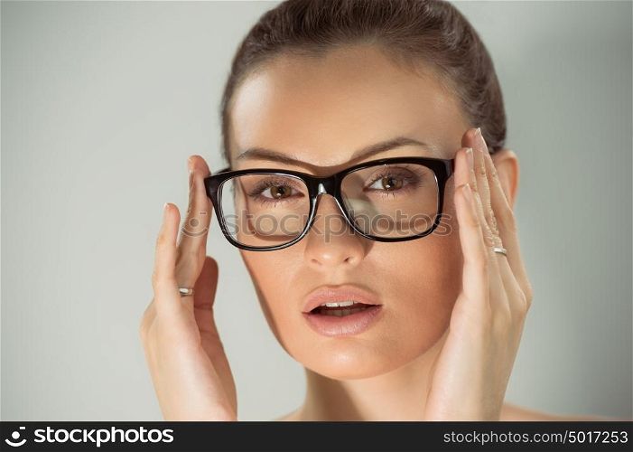 Beautiful young alluring woman wearing glasses. Studio shot against gray background