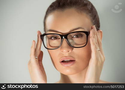 Beautiful young alluring woman wearing glasses. Studio shot against gray background