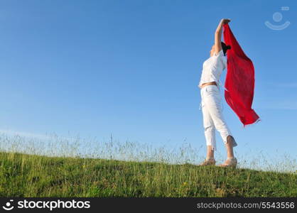 beautiful young and healthy woman run and jump on meadow at sunny day with red scarf