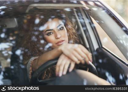 Beautiful young arabic woman inside a nice white car looking through the window. Arab girl wearing casual clothes.