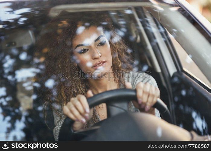 Beautiful young arabic woman inside a nice white car looking through the window. Arab girl wearing casual clothes.