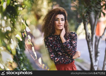 Beautiful young arabic woman with black curly hairstyle.. Beautiful young arabic woman with black curly hairstyle. Arab girl wearing casual clothes in the street.