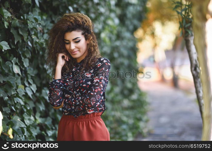 Beautiful young arabic woman with black curly hairstyle.. Beautiful young arabic woman with black curly hairstyle. Arab girl wearing casual clothes in the street.