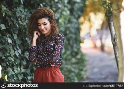 Beautiful young arabic woman with black curly hairstyle.. Beautiful young arabic woman with black curly hairstyle. Arab girl wearing casual clothes in the street.