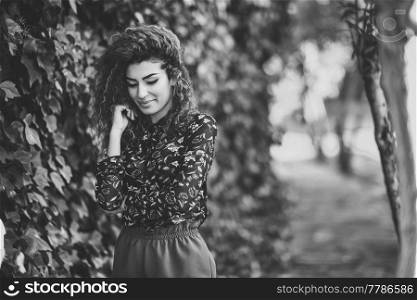 Beautiful young arabic woman with black curly hairstyle. Arab girl wearing casual clothes in the street.
