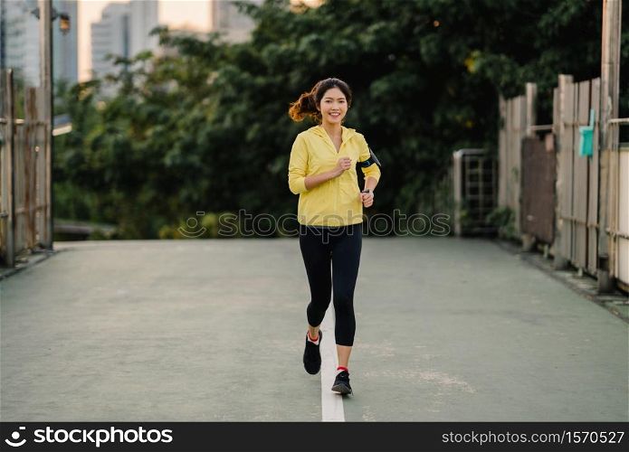 Beautiful young Asia athlete lady running exercises work out in urban environment. Japanese teen girl wearing sports clothes on walkway bridge in early morning. Lifestyle active sporty in city.