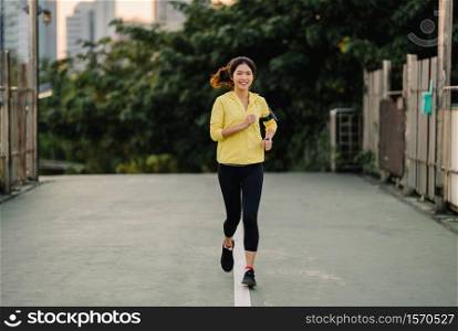 Beautiful young Asia athlete lady running exercises work out in urban environment. Japanese teen girl wearing sports clothes on walkway bridge in early morning. Lifestyle active sporty in city.
