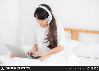 Beautiful young asia woman lying in bedroom using laptop computer showing video call chat at home, girl greet and listen and talking messenger, communication and lifestyle concept.