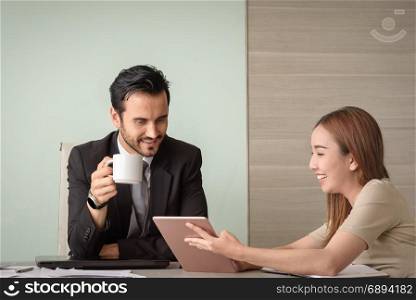 beautiful young asian business woman and caucasian man look at tablet for business project