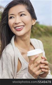 Beautiful young Asian Chinese woman or girl outside, smiling and drinking a takeaway cup of coffee or tea