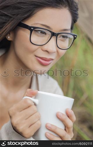 Beautiful young Asian Chinese woman or girl wearing glasses, outside, smiling and drinking a cup of coffee or tea