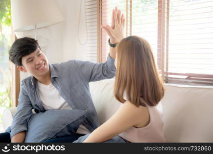 Beautiful young asian couple man and woman gesture hi five together with relax after work success on sofa, family celebration enjoy and excited with happy on couch, lifestyle concept.