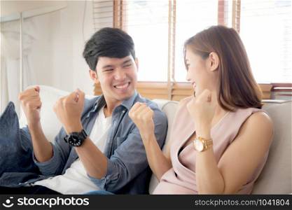 Beautiful young asian couple man and woman gesture together with relax after work success on sofa, family celebration enjoy and excited with happy on couch, lifestyle concept.