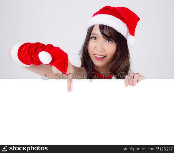 Beautiful young asian Santa woman holding blank board for xmas isolated on white background, asia girl show empty banner paper poster and pointing in Christmas holiday and new year for advertisement.