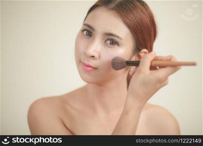 Beautiful young asian woman applying blusher