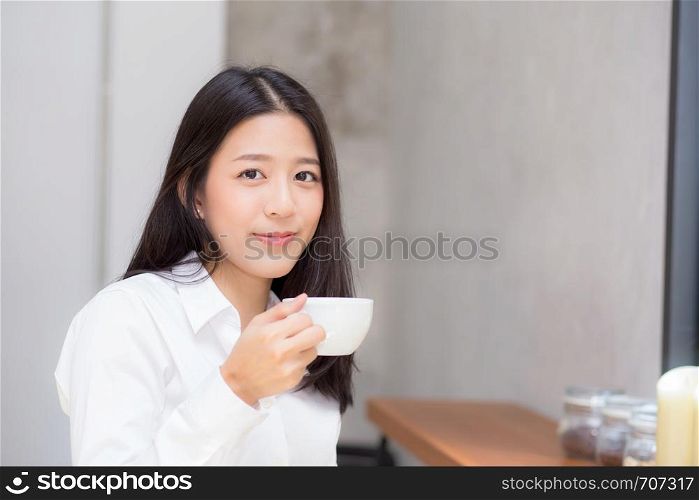 Beautiful young asian woman drinking coffee and smile in the morning at cafe, girl sitting in coffee shop for breakfast and leisure during free time.