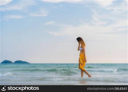 Beautiful young Asian woman happy relax walking on beach near sea. Lifestyle women travel on beach concept.