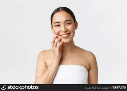 Beautiful young asian woman in towel standing in bathroom, smiling happy camera, touching clean skin, apply skincare products in bathroom, taking care of body, white background.. Beautiful young asian woman in towel standing in bathroom, smiling happy camera, touching clean skin, apply skincare products in bathroom, taking care of body, white background