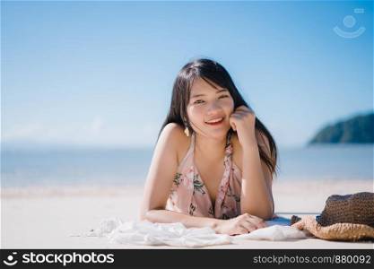 Beautiful Young Asian woman lying on beach happy relax near sea. Lifestyle women travel on beach concept.