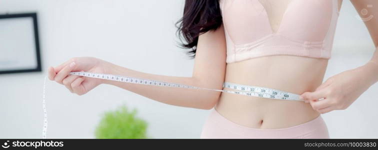 Beautiful young asian woman sexy body slim measuring abdomen for control weight loss in the room, beauty girl belly thin have cellulite with tape measure for diet, health concept, banner website.