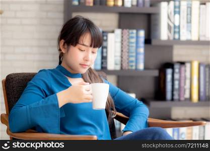 Beautiful young asian woman sitting on chair with comfort and relaxing in living room at home drinking a cup of coffee or tea or beverage, lifestyle asia girl leisure healthy and wellness for satisfied.